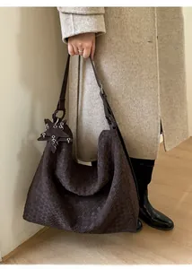 Detail of a dark brown woven hobo shoulder bag with a star leather charm ornament