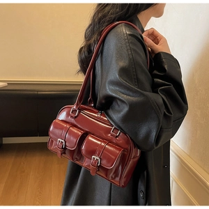 Detail view of burgundy faux leather shoulder bag with vintage buckles on a female model