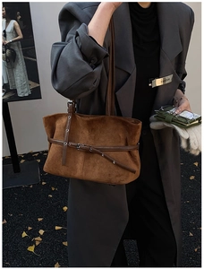 Vue latérale du sac fourre-tout en daim caramel porté avec un manteau gris chic