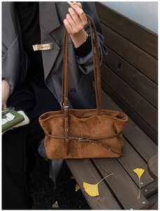 Gros plan d'un sac cabas en daim marron avec sangle en cuir et œillets métalliques