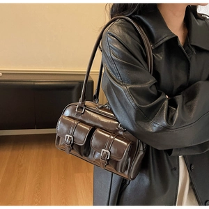Close-up of a retro dark brown glossy shoulder bag with dual front pockets and silver buckles