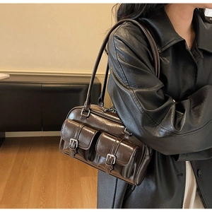 Detail of vintage dark brown faux leather shoulder bag with buckle pockets on side view