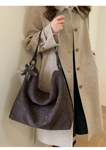 Detail of dark brown woven hobo bag with star charm worn with a beige wool coat