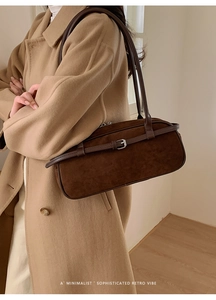 Detail of deep brown suede baguette bag featuring silver buckle and retro minimalist vibe