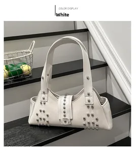Detailed view of white leather shoulder bag with polished silver-tone metal studs