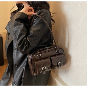 Detail of dark brown glossy shoulder bag featuring dual front pockets and silver buckles