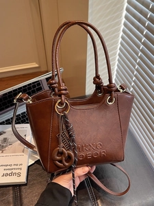Brown vintage faux leather crossbody bag with knot handles and embossed letter details