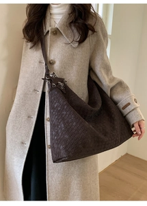 Detail of coffee brown woven tote bag featuring a leather star charm and metal rings