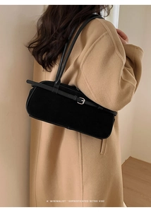 Detail of minimalist black baguette bag with suede texture and silver buckle strap