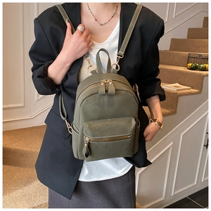 Olive green mini suede backpack featuring gold-toned zippers shown on a staircase