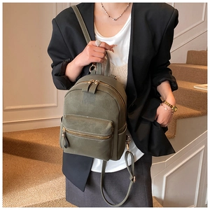 Detailed view of olive green mini backpack featuring white stitching and gold hardware