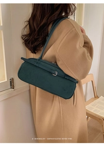 Detail of dark green matte leather baguette bag showing sleek retro minimalist texture