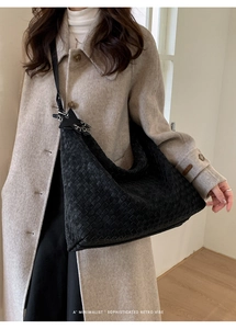 Detailed view of black woven leather hobo bag on shoulder for casual styling