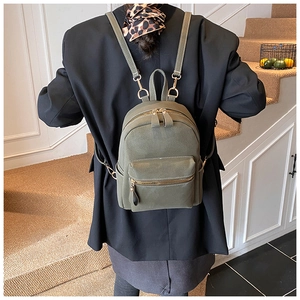 Detail of vintage dark green suede mini backpack showing metal hardware on female model