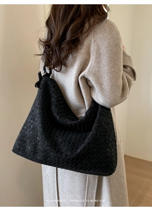 Detailed view of black woven leather hobo bag texture on model with minimalist style