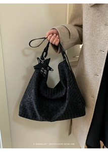 Detail of black woven leather hobo bag featuring a star pendant and minimalist texture