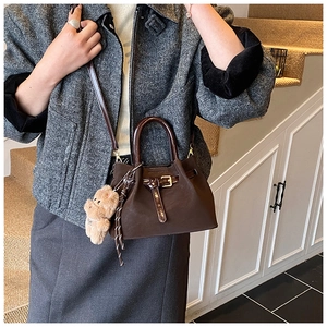Détail du sac seau rétro en daim marron foncé avec boucle et breloque ours en peluche