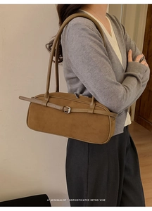 Macro view of a brown suede baguette bag featuring silver hardware and thin dual straps