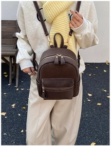Detail of vintage brown suede mini backpack with white stitching and gold hardware accents
