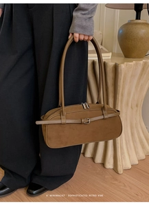 Detail of retro brown suede Boston bag with metal buckle and elongated dual handles