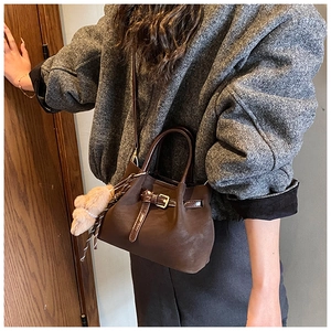 Détail du sac seau marron rétro en daim avec boucle décorative et breloque