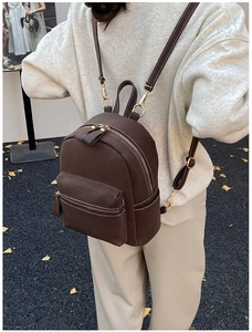Brown suede mini backpack with white stitching details worn on a model's back
