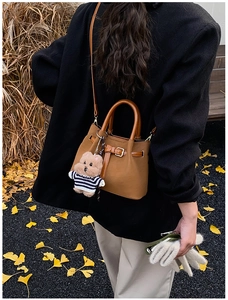 Détail d'un sac seau marron caramel avec un joli porte-clés en peluche d'ours rayé