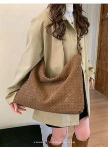Close-up of brown woven leather tote bag shown on a model in a minimalist setting