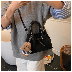 Détail du cabas en daim noir avec poignées brillantes et un pendentif ours en peluche