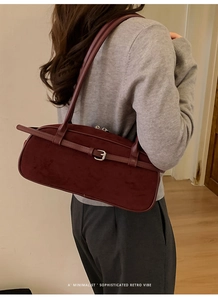 Close-up of retro burgundy suede baguette bag with buckle strap and zipper detail