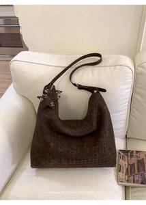 Macro shot of dark brown woven leather hobo bag with star charm detail on sofa