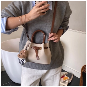 Détail du sac seau bicolore avec poignée marron et charmant pendentif d'ours en peluche