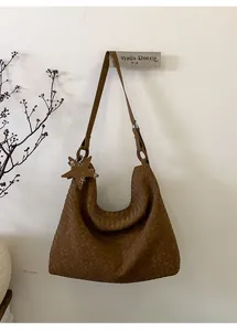 Detail of a brown woven leather hobo bag with star charm hanging on a minimal hook