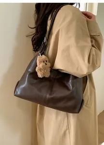 Detailed view of dark brown leather tote bag with cute plush puppy charm accessory