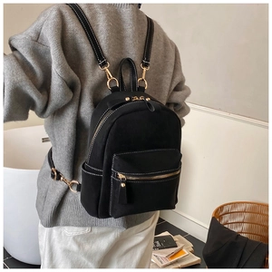Detail of black backpack with white contrast stitching and elegant golden hardware zipper
