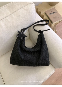 Detail of black woven leather hobo bag with star charm and metallic ring accents