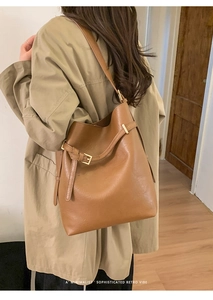 Sac seau marron minimaliste porté avec un trench-coat kaki pour un look rétro