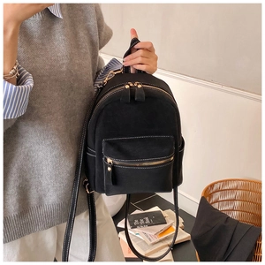Detail of a mini black canvas backpack with white topstitching and gold zipper hardware
