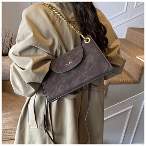 Detail of a charcoal faux leather crossbody bag with gold chain and vintage texture