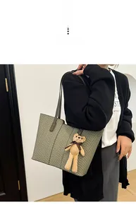 Detail of herringbone canvas tote bag with brown leather straps and bear charm