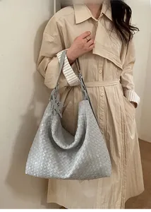 Close-up of light grey-blue woven leather tote bag featuring a star charm detail
