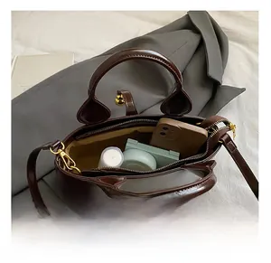 Interior view of small square bag showing storage for phone, powder, and cosmetics