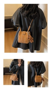 Détail du sac seau en daim marron avec surpiqûres blanches et charme d'ours