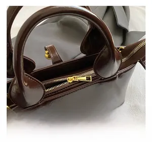 Detail of dark brown oil wax leather handbag with premium gold metal zipper closure