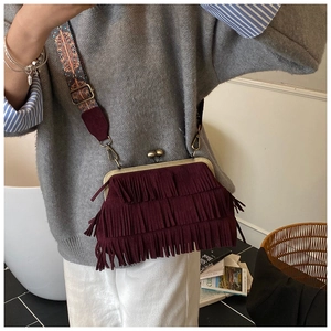 Detail van bordeauxrode crossbodytas met franjes, gouden sluiting en etnische riem