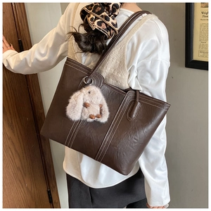 Braune Leder-Tote-Bag mit weißen Kontrastnähten und weißem Plüsch-Hasen-Anhänger