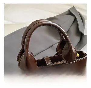 Close-up of caramel brown leather handbag featuring gold zipper and vintage buckle strap