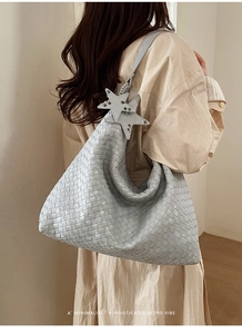 Detail of light blue woven hobo bag with leather intrecciato texture and star charms