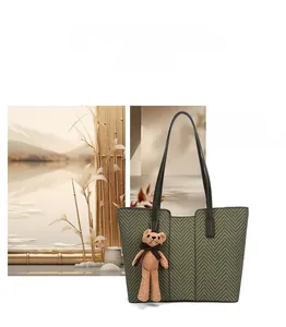 Detail of dark grey woven tote bag with herringbone pattern and brown bear charm pendant