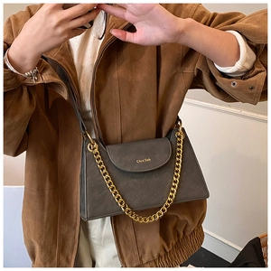 Detail of dark grey crossbody bag featuring golden chain and brand logo on flap cover